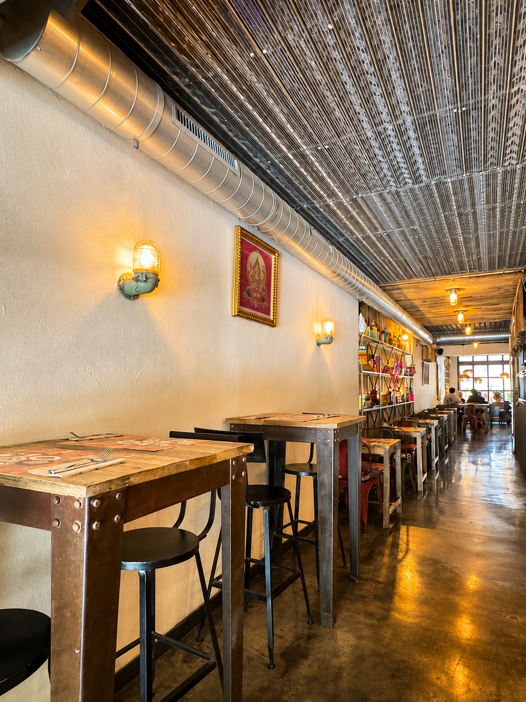 Long white-wall dining corridor with high tables at THAI ISAAN